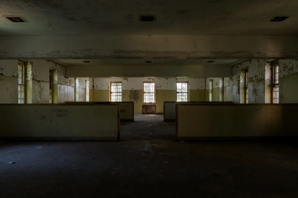 Abandoned wing of Creedmoor Hospital, Queens New York with long row of windows and 'Reading Room' visible on wall